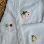 Motifs brodés sur un teeshirt : une tulipe et des oranges.