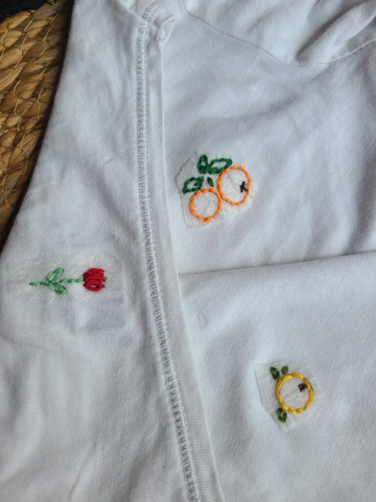 Motifs brodés sur un teeshirt : une tulipe et des oranges.