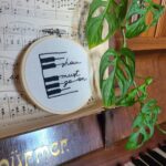 Broderie décorative sur le thème de la musique, motif piano avec phrase Show must go on.
