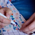 Gros plan sur un main qui trace des repères au feutre pour coudre